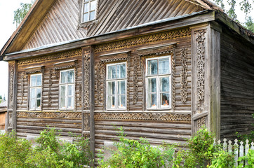 Fototapeta na wymiar Traditional old Russian wooden house with carved wooden trim in Novgorod region, Russia
