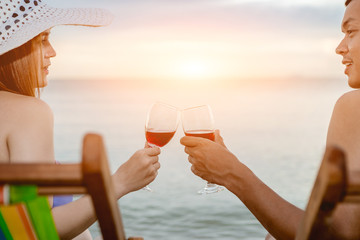Asian couple walking on the beach when the sun is about to sunset during the honeymoon. There are  Couple walking on Valentine's Day and drinking the wine.