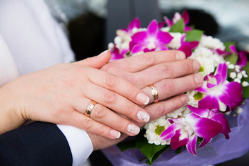 Obraz na płótnie Canvas Bride and groom hands with wedding rings and beautiful bridal bouquet