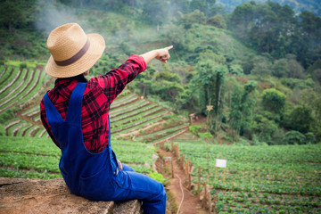 A young farmer pointing in a Strawberry farm