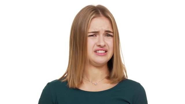 Close up portrait of discontented female in casual clothes feeling aversion looking with displeased expressions demonstrating her disgust over white background in studio. Concept of emotions