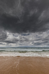 stormy sea with sandy beach and dark clouds