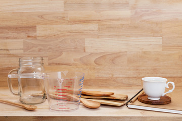 measuring cup and wooden spoon, cooking supplies on wood background