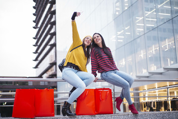 Fototapeta na wymiar Two women friends taking a selfie in street after shopping