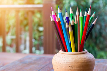 Assortment color pencil in pot on wooden table with copy space.