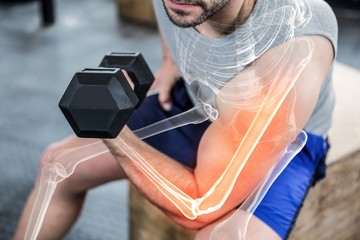 Highlighted arm of strong man lifting weights at gym