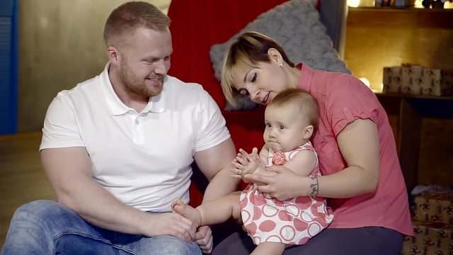 young family with a child at home playing in hands baby. sit on the floor in the cozy interior