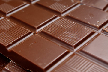 Chocolate bar and bars as background. Milk and dark shiny chocolate texture. Stack chocolates pattern. Stunning beautiful cacao brown dessert sweets.