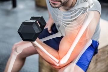 Highlighted arm of strong man lifting weights at gym