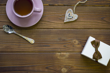 Still life with a tea cup, spoon, heart shaped gingerbread on a rustic wooden background, top view