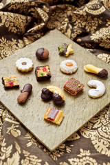 Weihnachtsbäckerei: Verschiedene Weihnachtskekse auf einer goldenen Platte auf einer festlichen Tischdecke