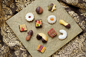 Weihnachtsb&auml;ckerei: Verschiedene Weihnachtskekse auf einer goldenen Platte auf einer festlichen Tischdecke