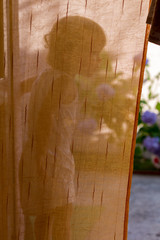 Little girl on the balcony behind the courtain