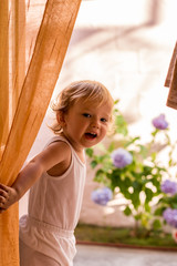 Little girl on the balcony behind the courtain