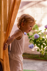 Little girl on the balcony behind the courtain