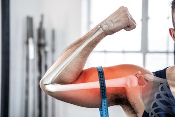 Highlighted arm of man measuring biceps with measuring tape