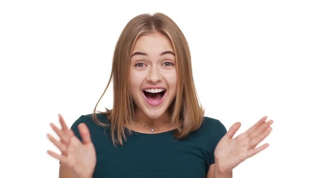Portrait of beautiful woman with caucasian appearance expressing  unexpectedness shouting in amazement or astonishment keeping hands on face over white background slomo. Concept of emotions