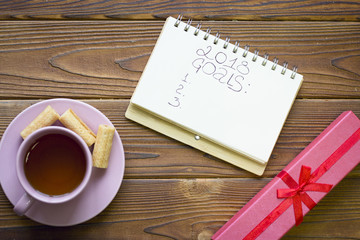 2018 goals planning with a pink tea cup and a red giftbox on a rustic wooden table, top view