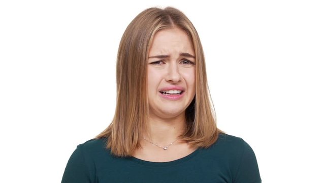 Close up studio portrait of displeased female with auburn hair feeling aversion demonstrating her disgust meaning rejection over white background in slow motion. Concept of emotions