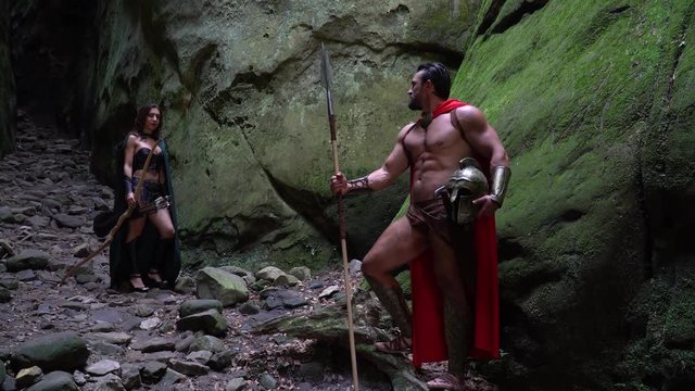 Full length shot of a medieval warrior in battledress walking through the forest with his woman female archer fighters soldiers couple love romance historical characters.