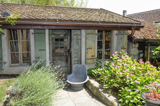 Ancienne cabane de jardin et vieille baignoire en fer dans un jardin fleuri
