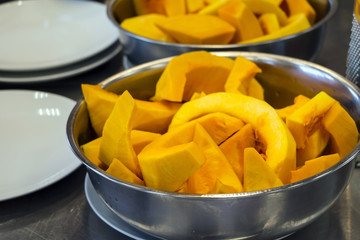 Raw cut pumpkin in metal bowls ready for cooking. Closeup. Selective focus.