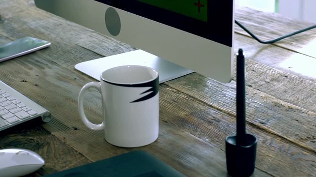 Closeup on a caucasian male freelance designer, programer working at Home typing on a wireless keyboard with electronics peripheral on the wooden table