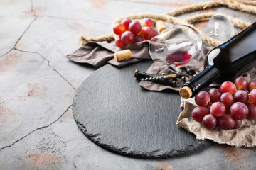 Bottle, corkscrew, glass of red wine, grapes on a table