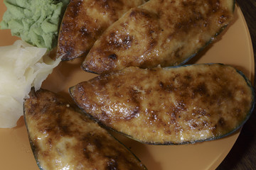 Baked stuffed mussels on an orange dish. Japanese seafood