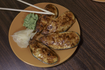 Baked stuffed mussels on an orange dish. Japanese seafood