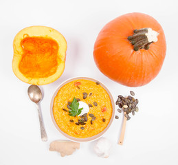 Pumpkin soup and pumpkins, pumpkin seeds, ginger and garlic on a white background