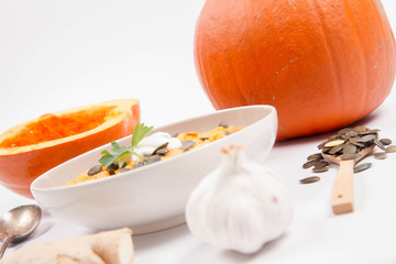 Pumpkin soup and pumpkins, pumpkin seeds, ginger and garlic on a white background
