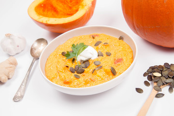 Pumpkin soup and pumpkins, pumpkin seeds, ginger and garlic on a white background