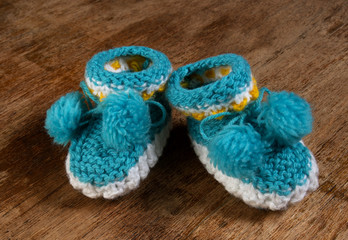 Colorful knitted baby booties on a wooden board.