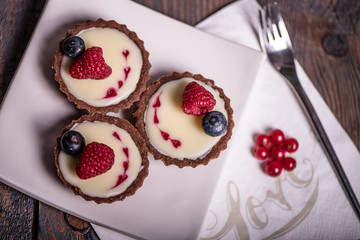 chocolate cupcakes with white cream and red hearts decorated with raspberry and blueberry