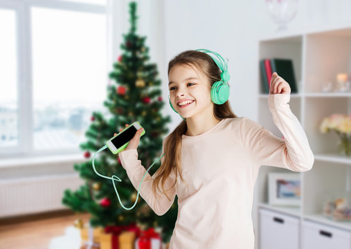 girl with smartphone and headphones at christmas