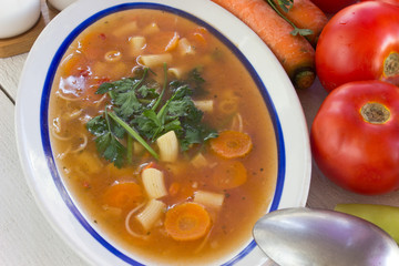 Minestrone soup in plate on white wooden table