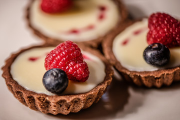 chocolate cupcakes with white cream and red hearts decorated with raspberry and blueberry