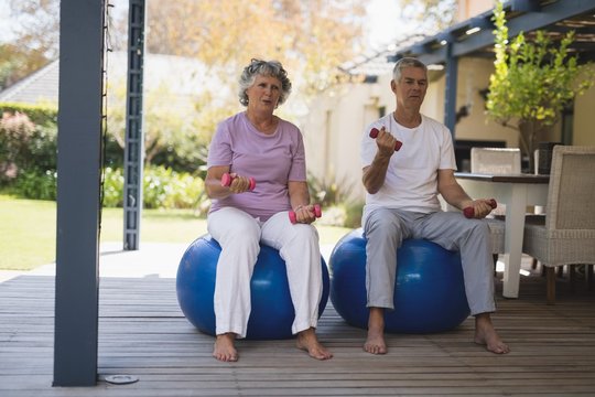Full length of senior couple exercising at porch - Powered by Adobe