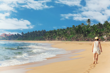 Young and Beautiful Woman Walking on the Beach near the Ocean and Looking Far Away