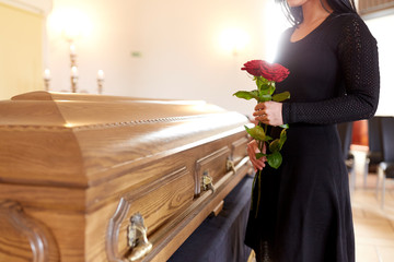 woman with red roses and coffin at funeral - obrazy, fototapety, plakaty