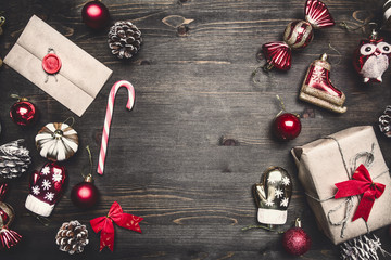 Christmas frame, lined with Christmas toys, a gift and an envelope, on a wooden rustic background, top view