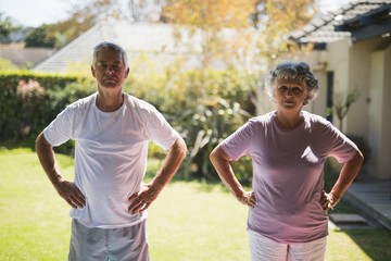 Senior couple with hands on hip exercising on sunny day