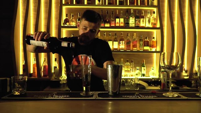 Bearded barman pours syrup into a cocktail glass, bit slow motion. Slider shooting