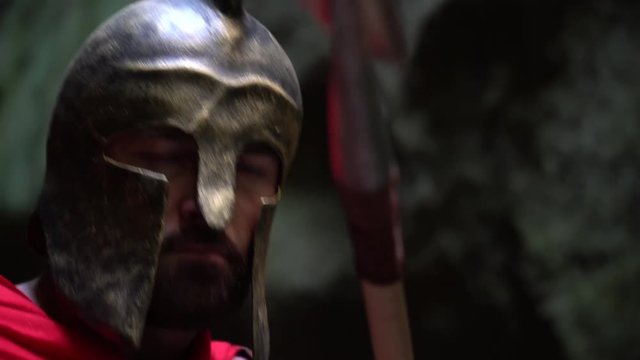 Closeup of a mature spartan soldier wearing a helmet hiding behind his shield looking to the camera fiercely holding a spear ready to fight bravery confidence masculinity concept.