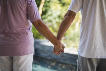 Obraz premium Mid section of senior couple holding hands