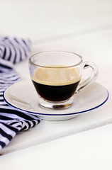 Tazza in vetro di caffè espresso su tavolo bianco. Sfondo luminoso