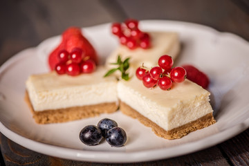 cheescake on a white plate decorated with fruit and red berries