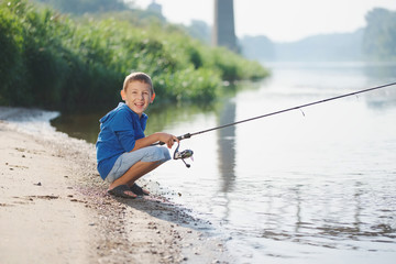 happy boy with rod on coast of river