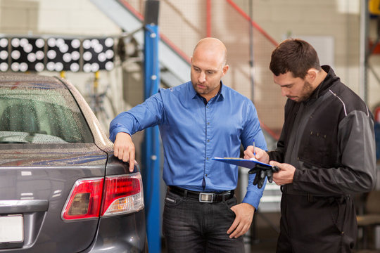 mechanic and customer looking at car taillight